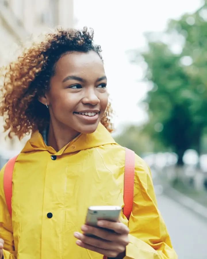 Cliente souriante, un café et son téléphone à la main