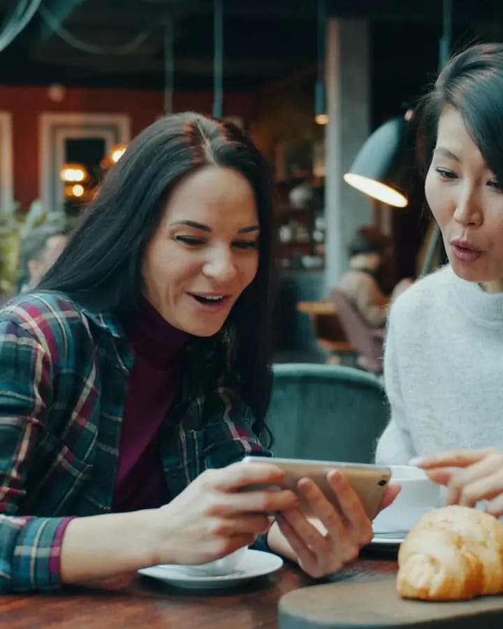 Deux amies qui regardent un téléphone au café